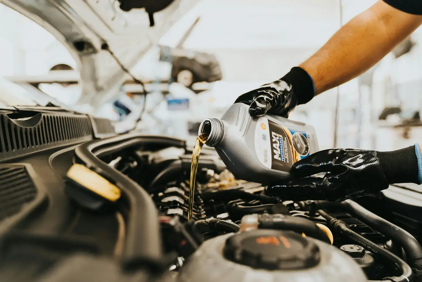 a person pouring oil into a car engine